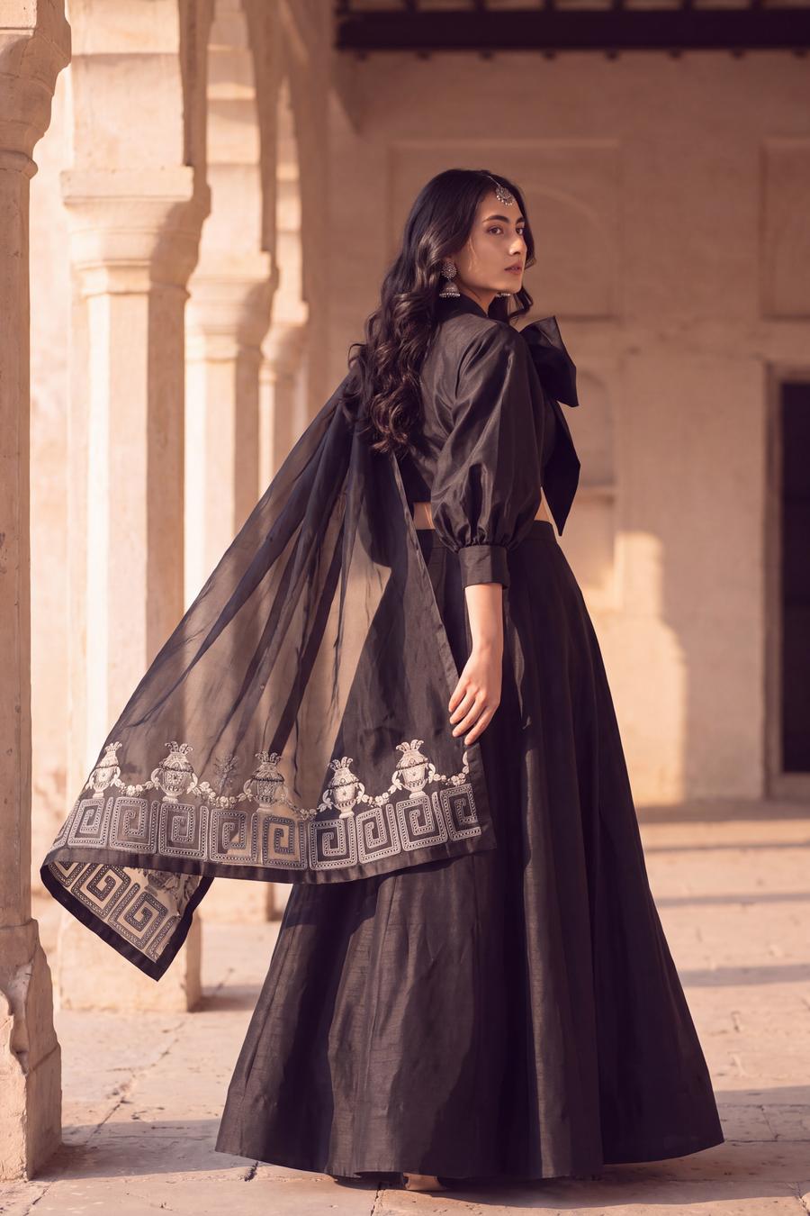 Back view of black raw silk lehenga with bow top, sheer organza dupatta draped over the shoulder