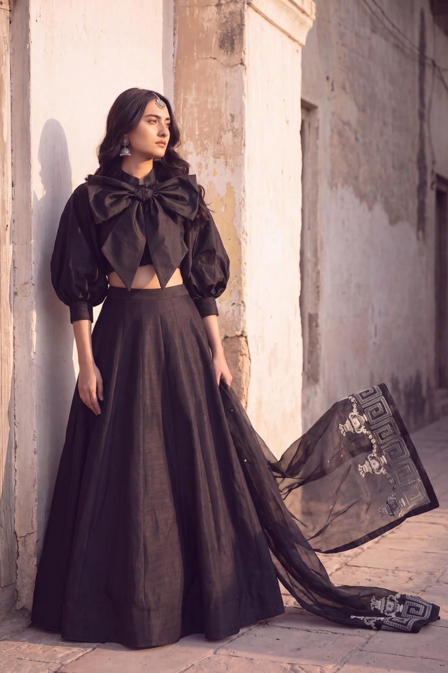 Black bow crop top and raw silk lehenga, organza dupatta trailing to show its silver border motif