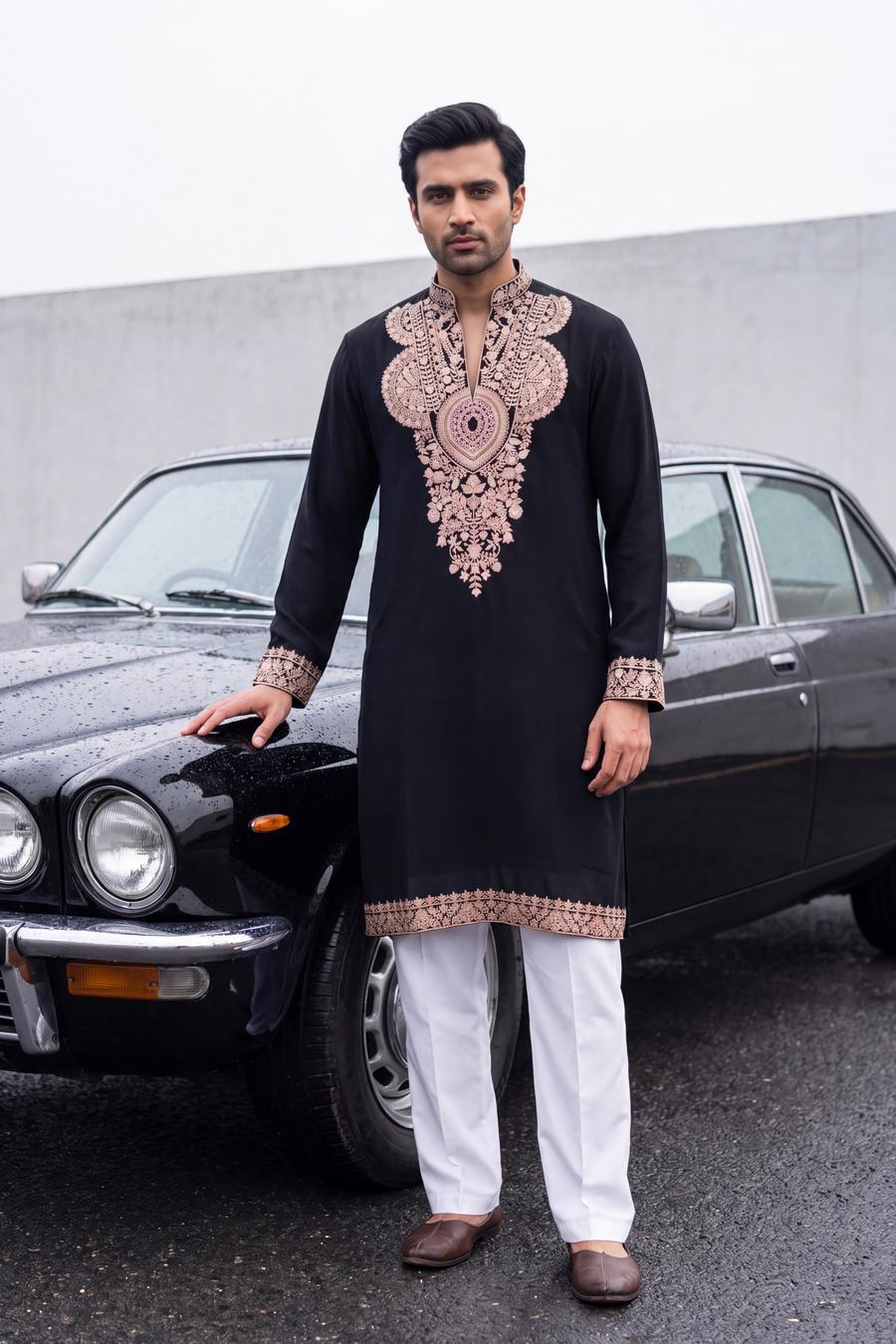 Black embroidered kurta with white shalwar worn beside a vintage car in a black and white street scene