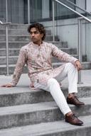 Blush pink embroidered kurta with white shalwar, model seated in a cool toned city setting