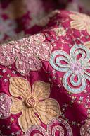 Close up of fuchsia silk with rose, camel, sky blue and olive florals outlined in gold, seed beads