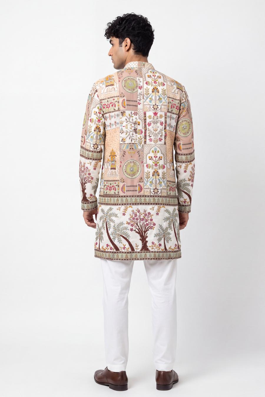 Back view of the ivory kurta with patchwork blocks above the hip band and embroidered trees below