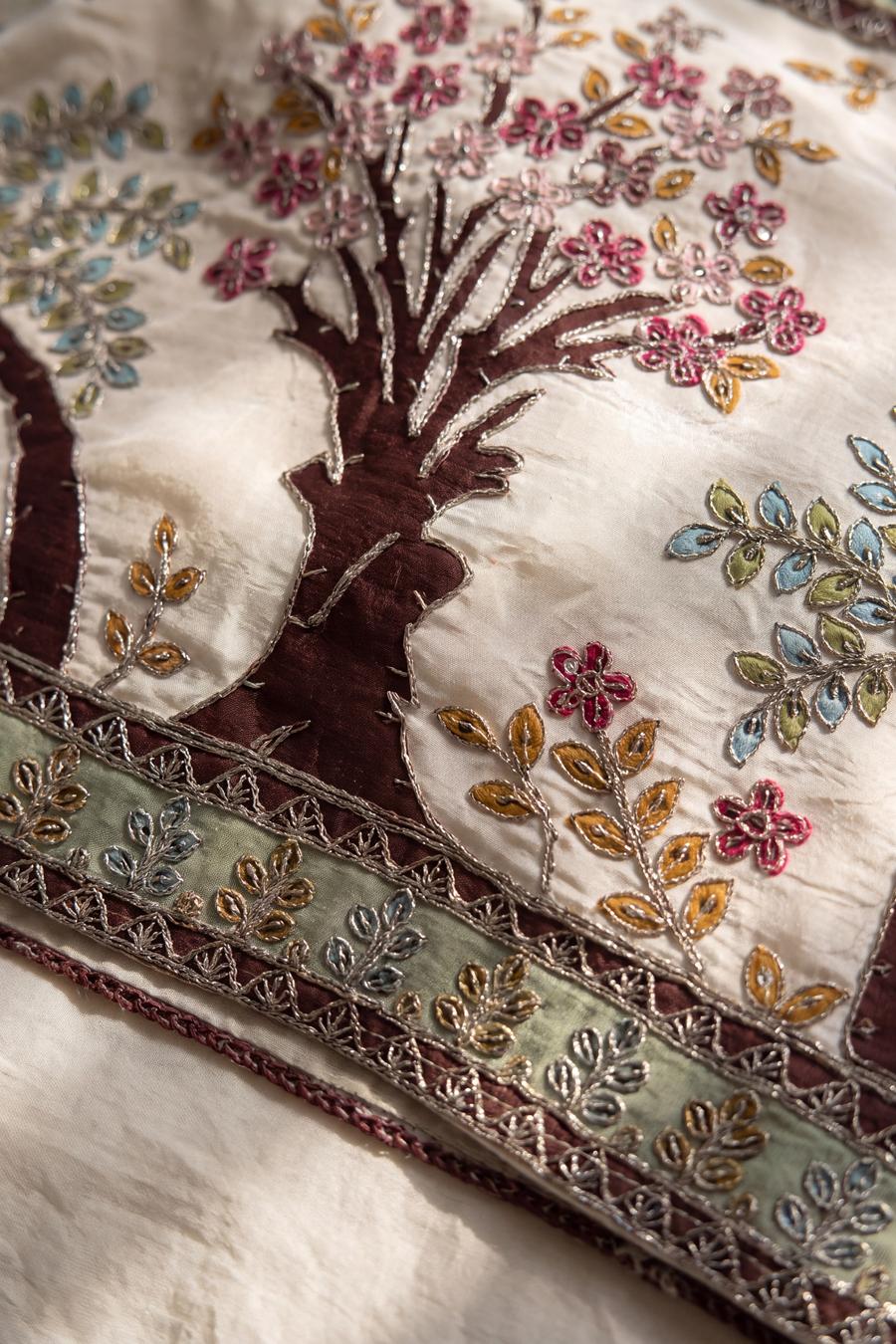 Close up of the ivory kurta patchwork: elephant, pavilion and floral motifs traced in silver