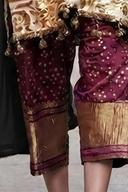 Wine embroidered trousers with gold dot work and gold hem border, close-up of the lower legs