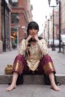 Ivory gold muqesh shirt seated, wine trousers with wide gold borders at the hem in view