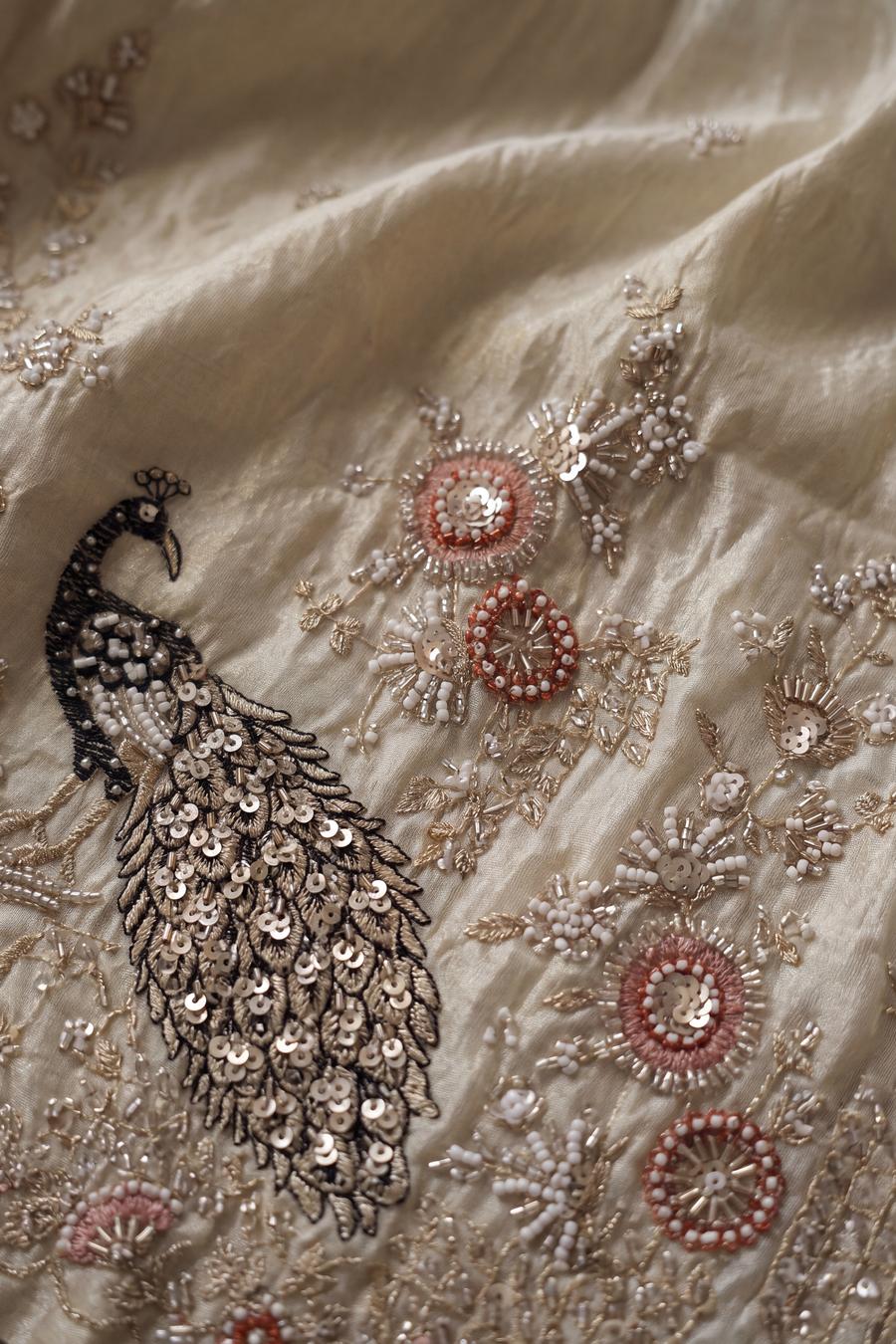 Close up of the ivory kurta hem: embroidered peacock, coral bead rosettes and scalloped beaded edge