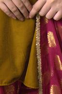 Marigold velvet kurta, close up of the gold trim edge against the magenta farshi shalwar