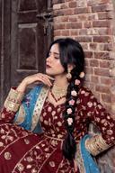 Maroon and gold anarkali with blue organza dupatta, seated side view showing sleeve and braid