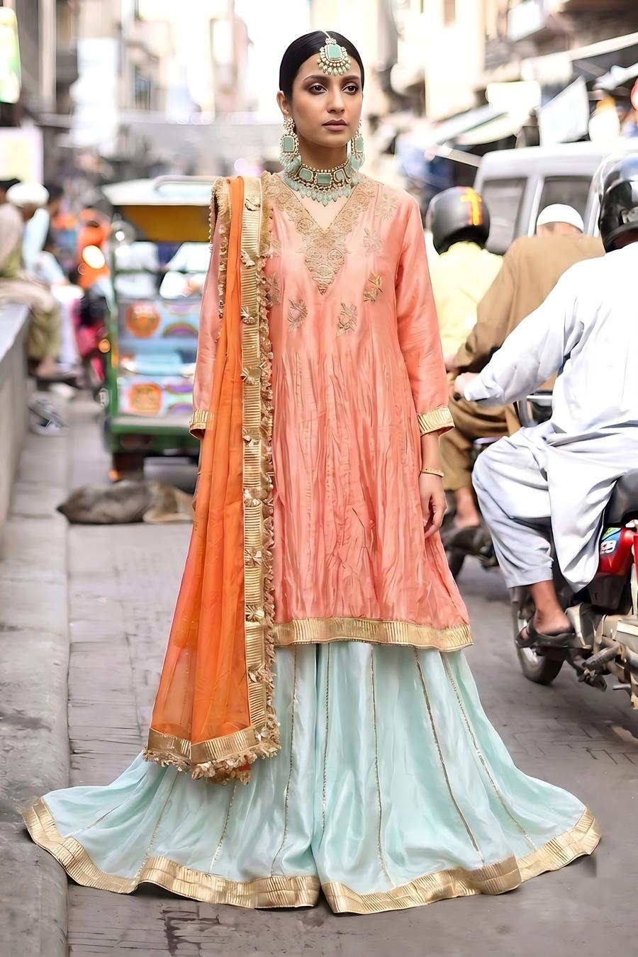 Mint farshi lehenga with tangerine silk shirt and orange dupatta, full length front view with a mint choker and tikka