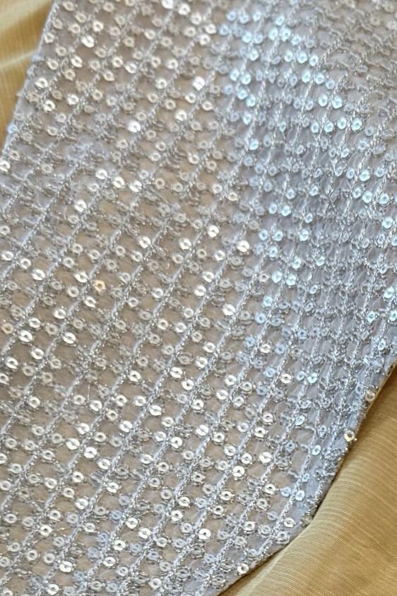 Mustard long shirt, close up of the silver sequin lattice over a gold lining