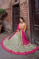 Sage floral lehenga seated on the ground, skirt spread wide to show the full magenta border