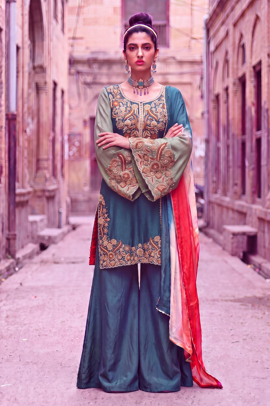 Teal kurta with tangerine and green handwork and wide teal palazzo, arms crossed, full length